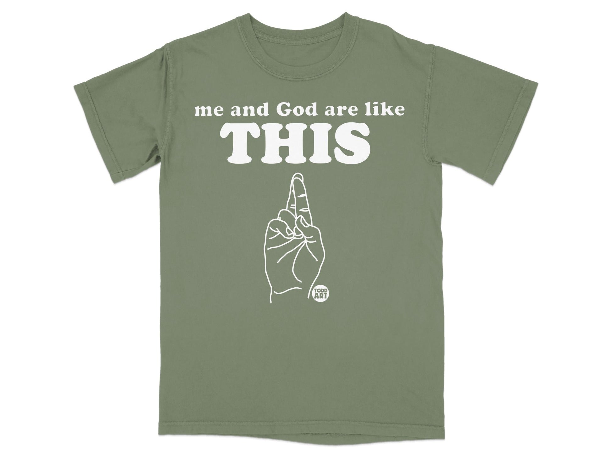 Olive green t-shirt with white text "me and God are like THIS" and line art hand.