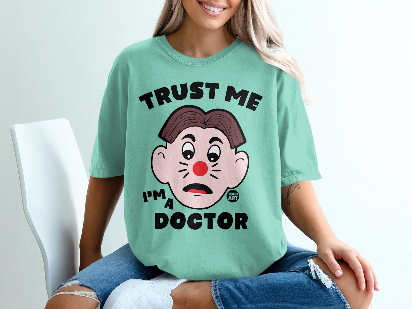 Teal t-shirt with cartoon face and "TRUST ME I'M A DOCTOR" text.