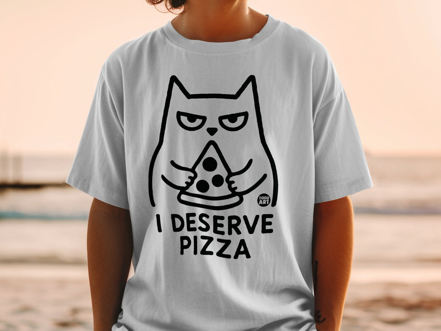 T-shirt with black outline of a cat holding a slice of pizza, text "I DESERVE PIZZA".