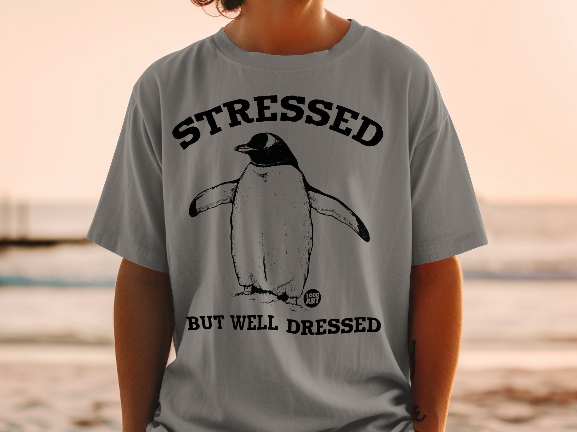 Penguin wearing a suit on a t-shirt reading "STRESSED BUT WELL DRESSED".