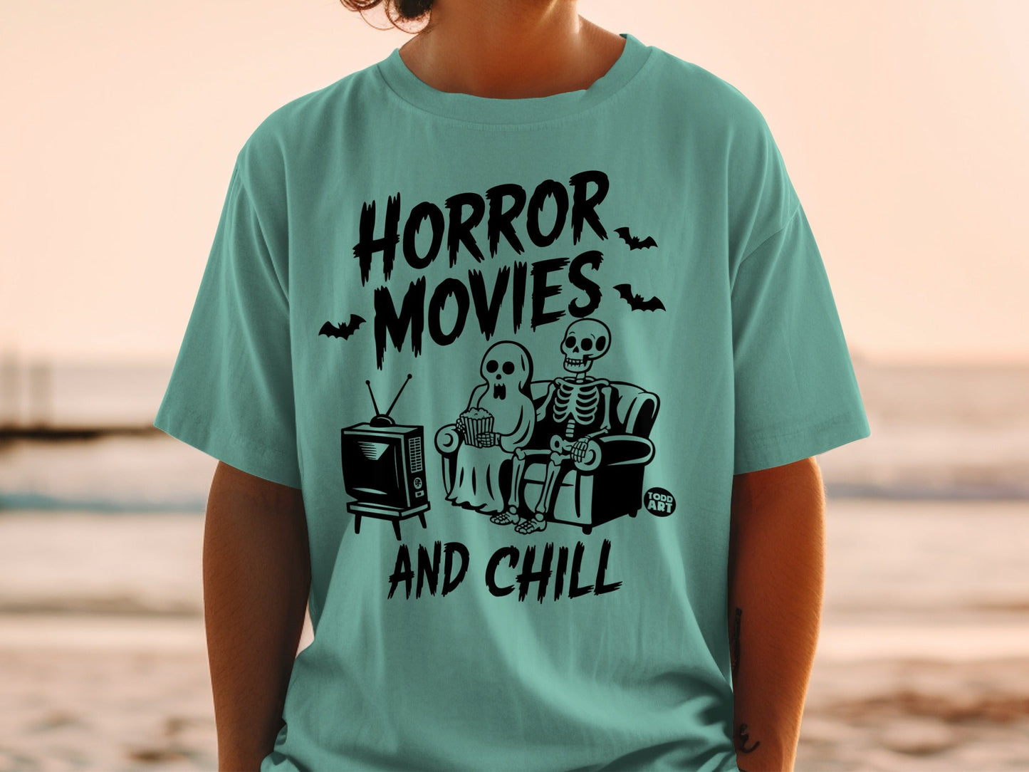 Skeleton couple watching horror movies and eating popcorn on teal t-shirt.