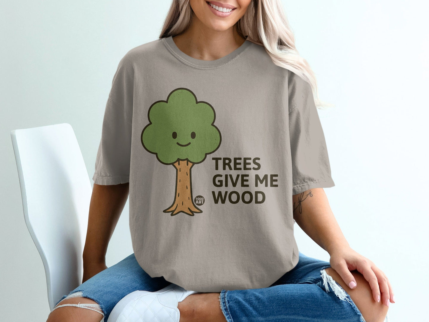 Beige t-shirt with green cartoon tree and text "TREES GIVE ME WOOD".