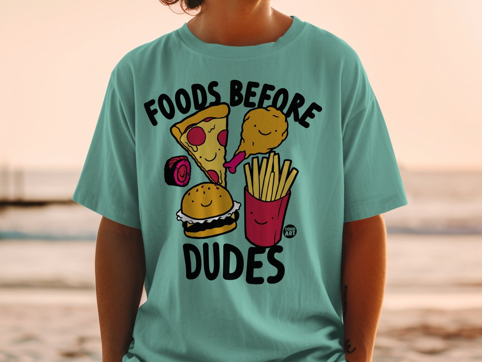 Teal t-shirt with cartoon pizza, sushi, burger, and fries, saying "Foods Before Dudes".