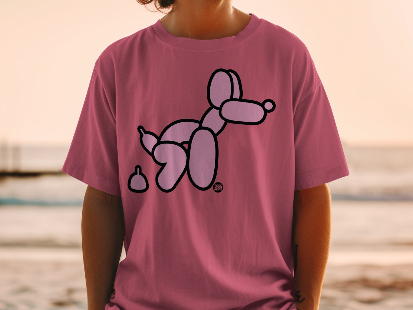 Pink t-shirt with a black balloon dog and poop graphic.
