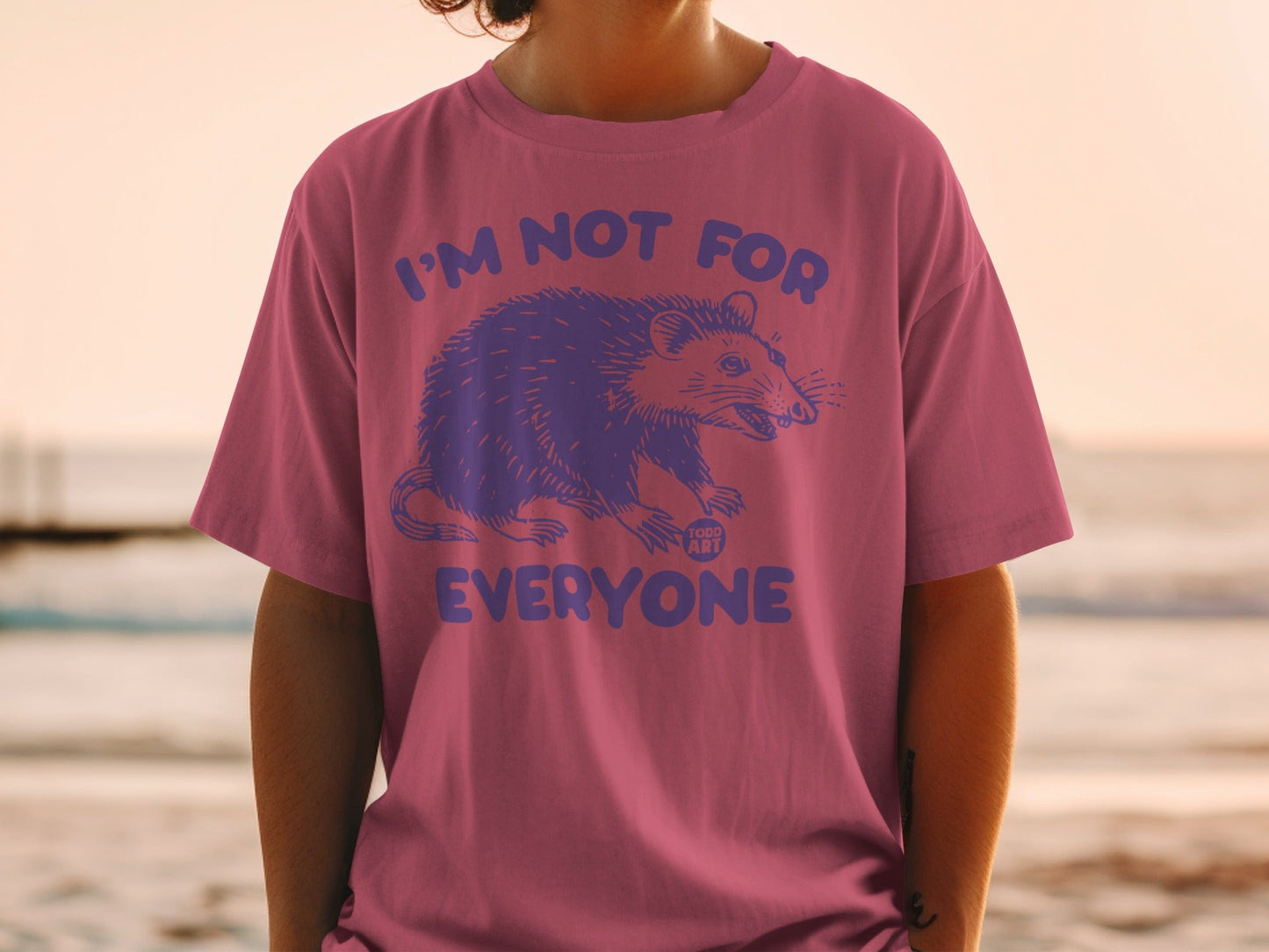 Pink t-shirt with a purple opossum graphic and text "I'M NOT FOR EVERYONE".