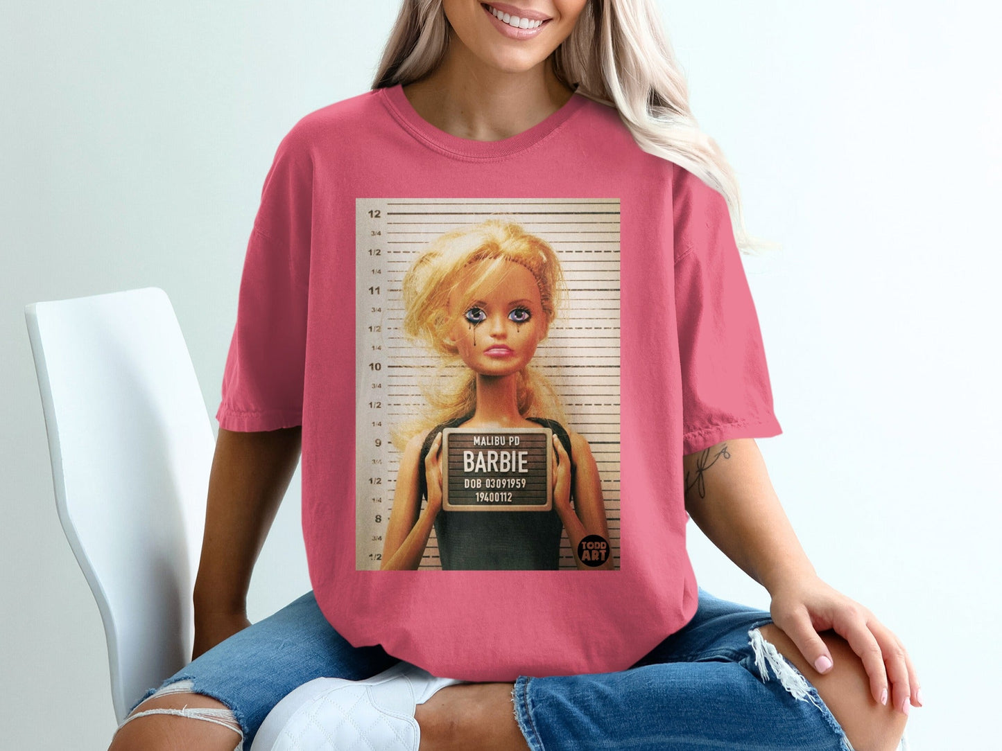 Pink t-shirt with a Barbie mugshot graphic and text.