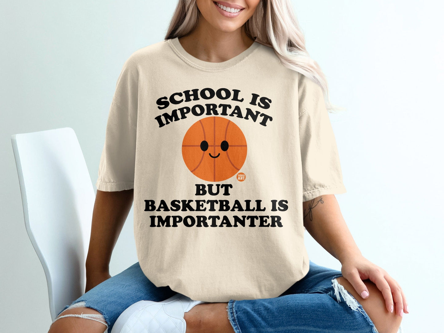 Cream t-shirt with smiling basketball and "School is important but basketball is importanter" text.