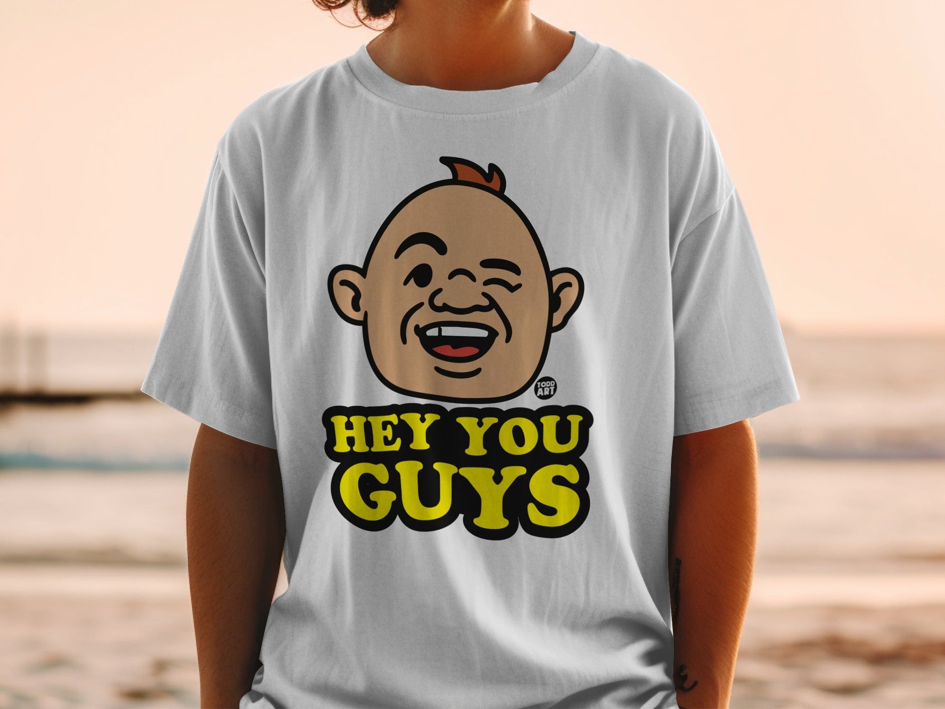 White t-shirt with a cartoon character's face and "Hey You Guys" text.
