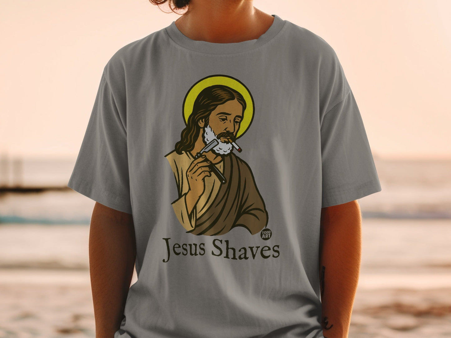 Grey t-shirt with "Jesus Shaves" graphic of Jesus with a razor and cigarette.