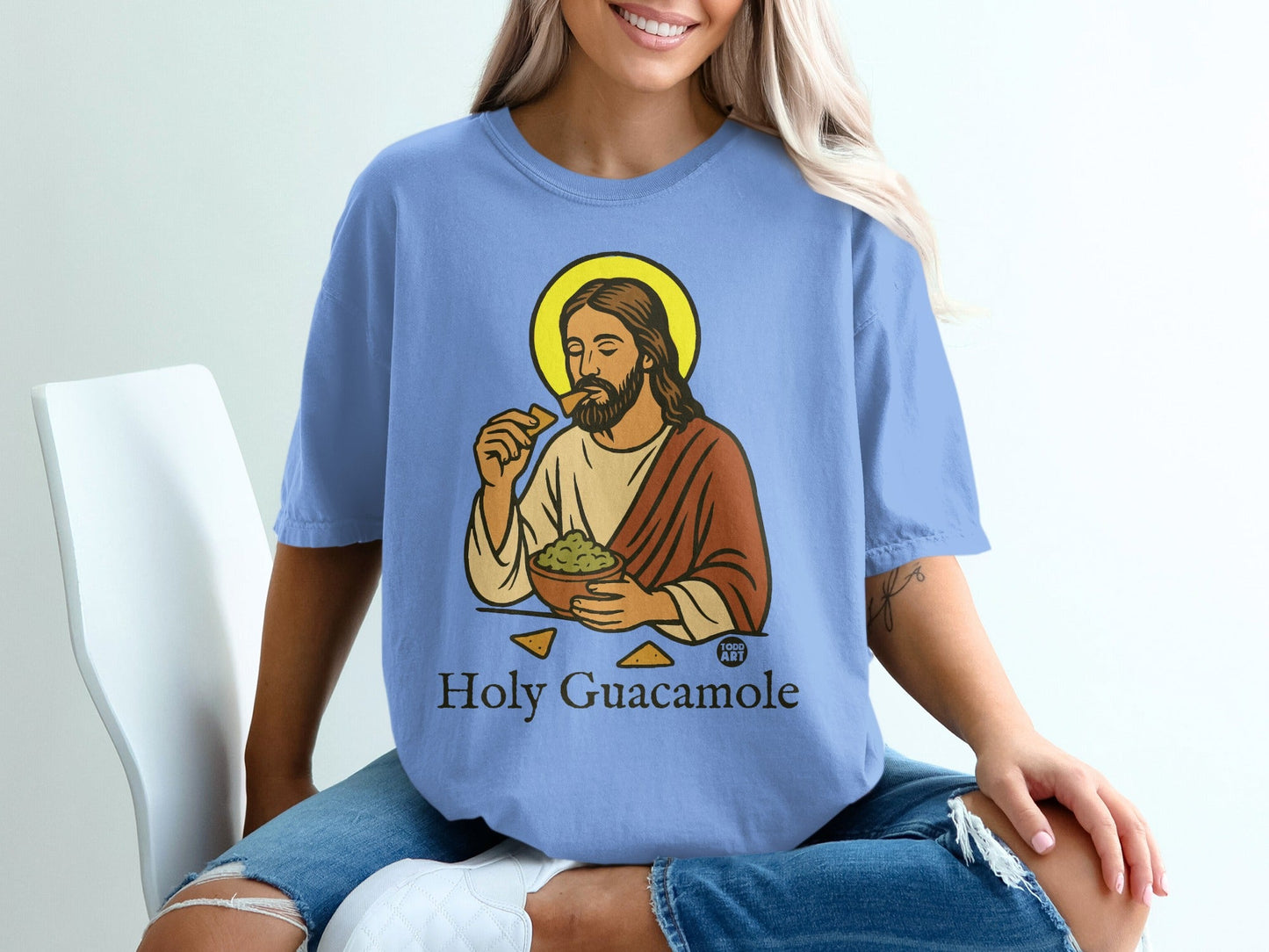 Jesus with halo eating chips and guacamole on a light blue t-shirt.