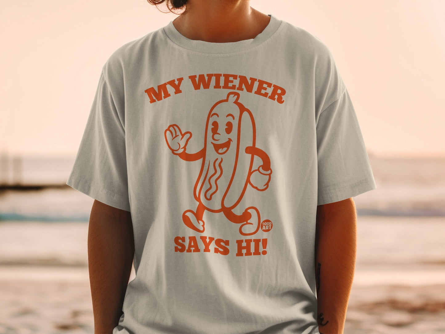 Orange t-shirt with a cartoon hot dog that says "My Wiener Says Hi!".