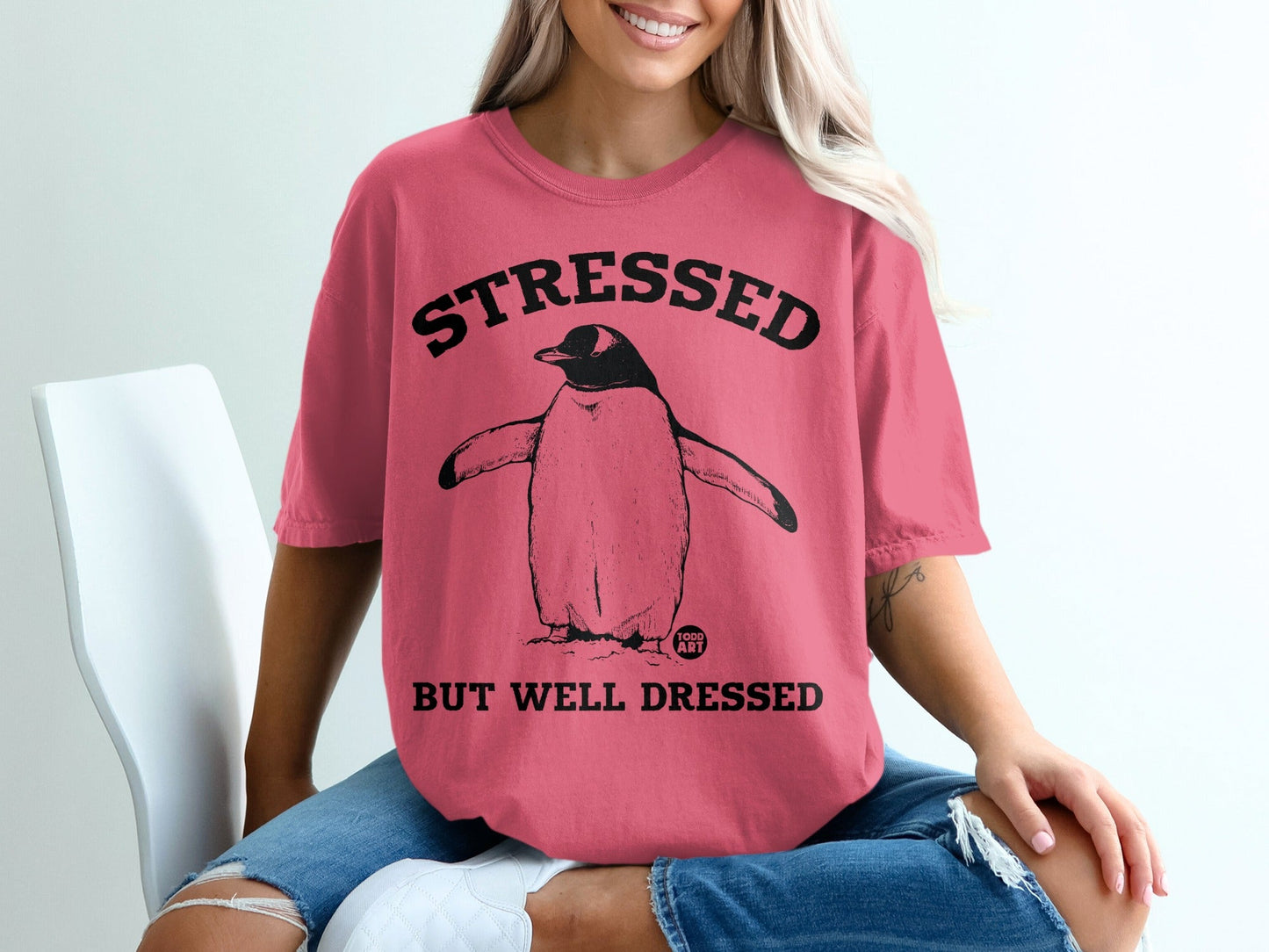 Pink t-shirt with "STRESSED BUT WELL DRESSED" and a penguin graphic.