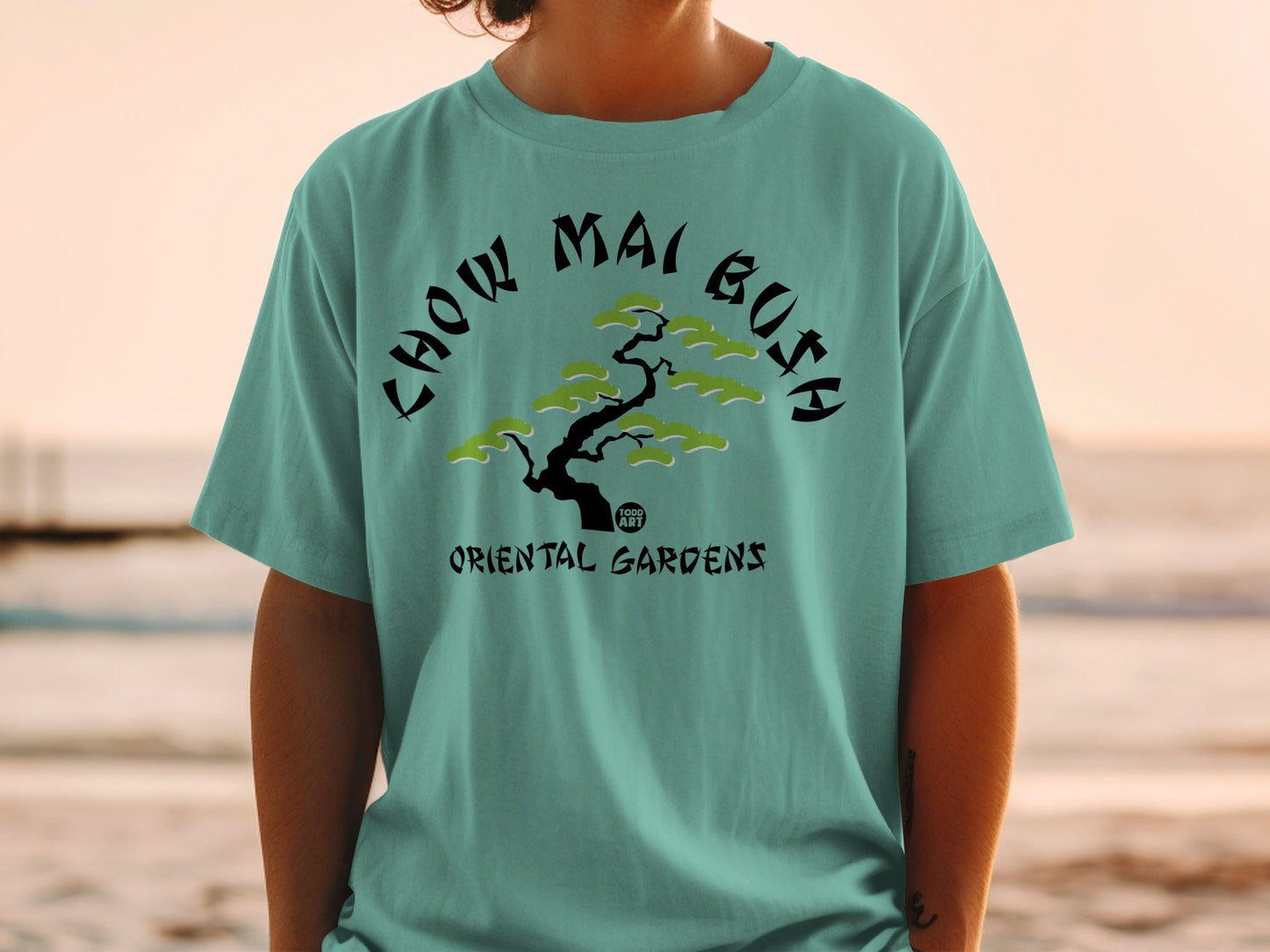 Teal t-shirt with black text and a stylized green tree graphic.
