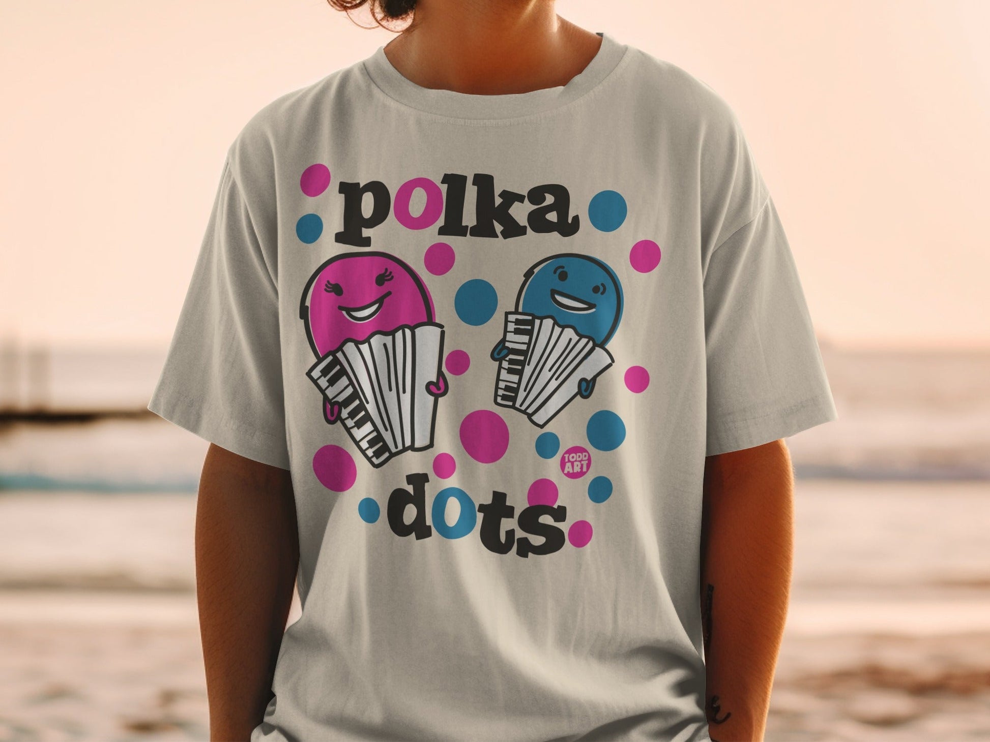 Grey t-shirt with pink and blue polka dot cartoon accordions and "polka dots" text.