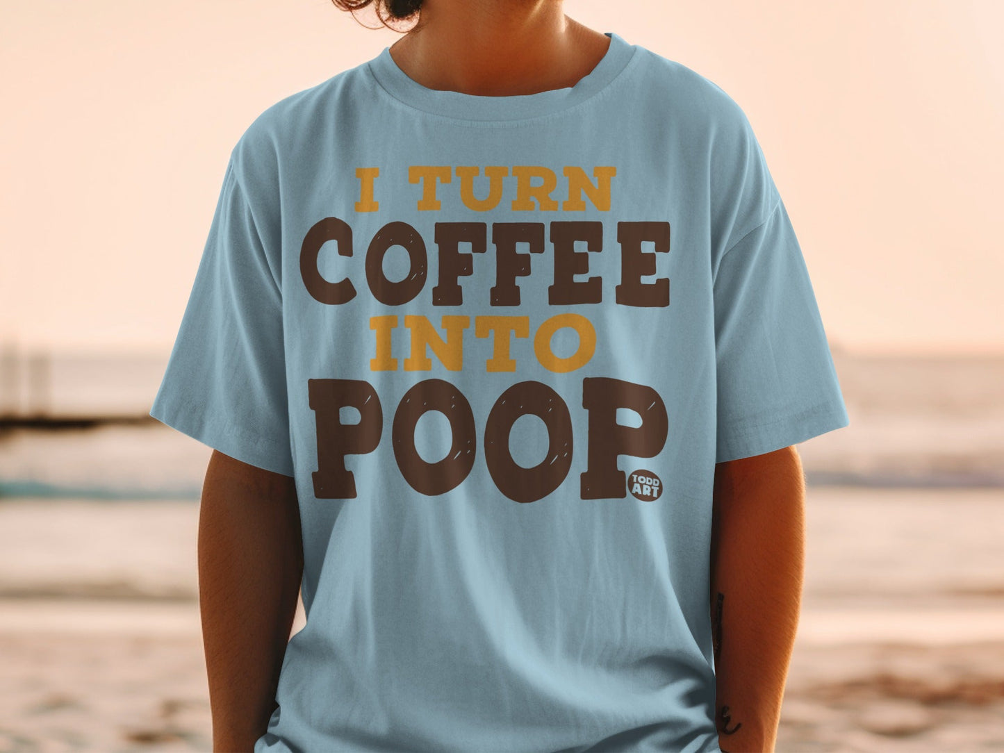 Light blue t-shirt with "I TURN COFFEE INTO POOP" printed in brown and orange.