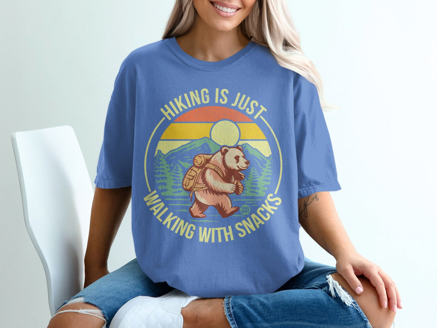 Blue t-shirt with a bear hiking with snacks graphic and text.