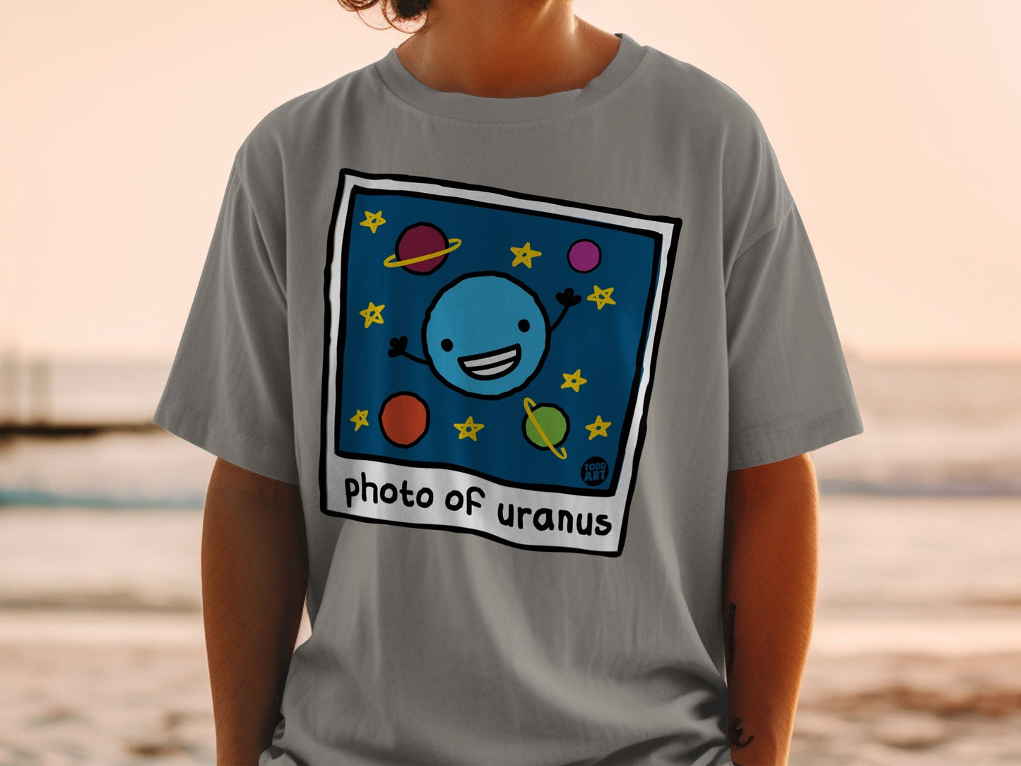 T-shirt with cartoon illustration of a smiling planet Uranus and stars.