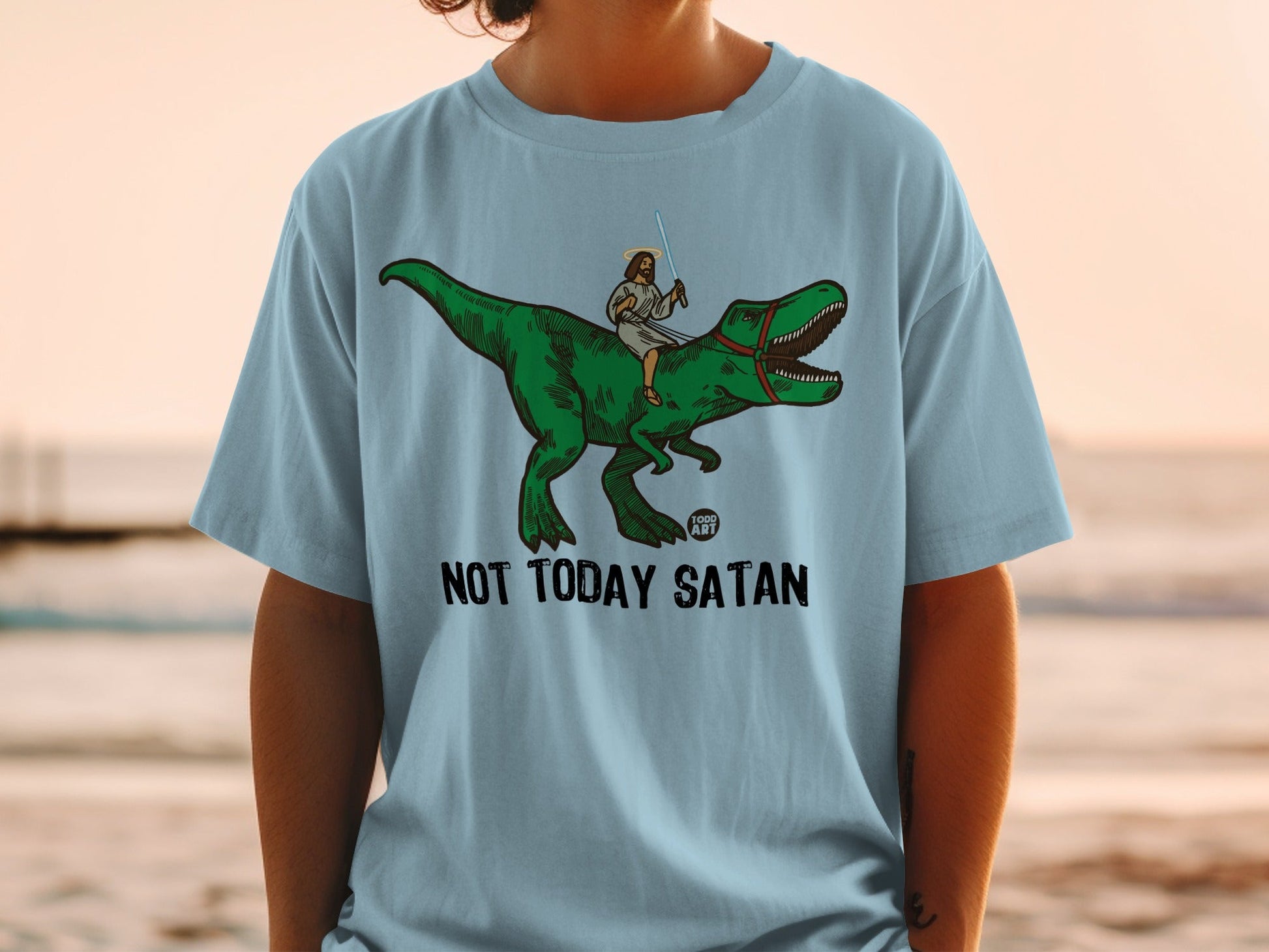 Light blue t-shirt with Jesus riding a dinosaur, "Not Today Satan" text.