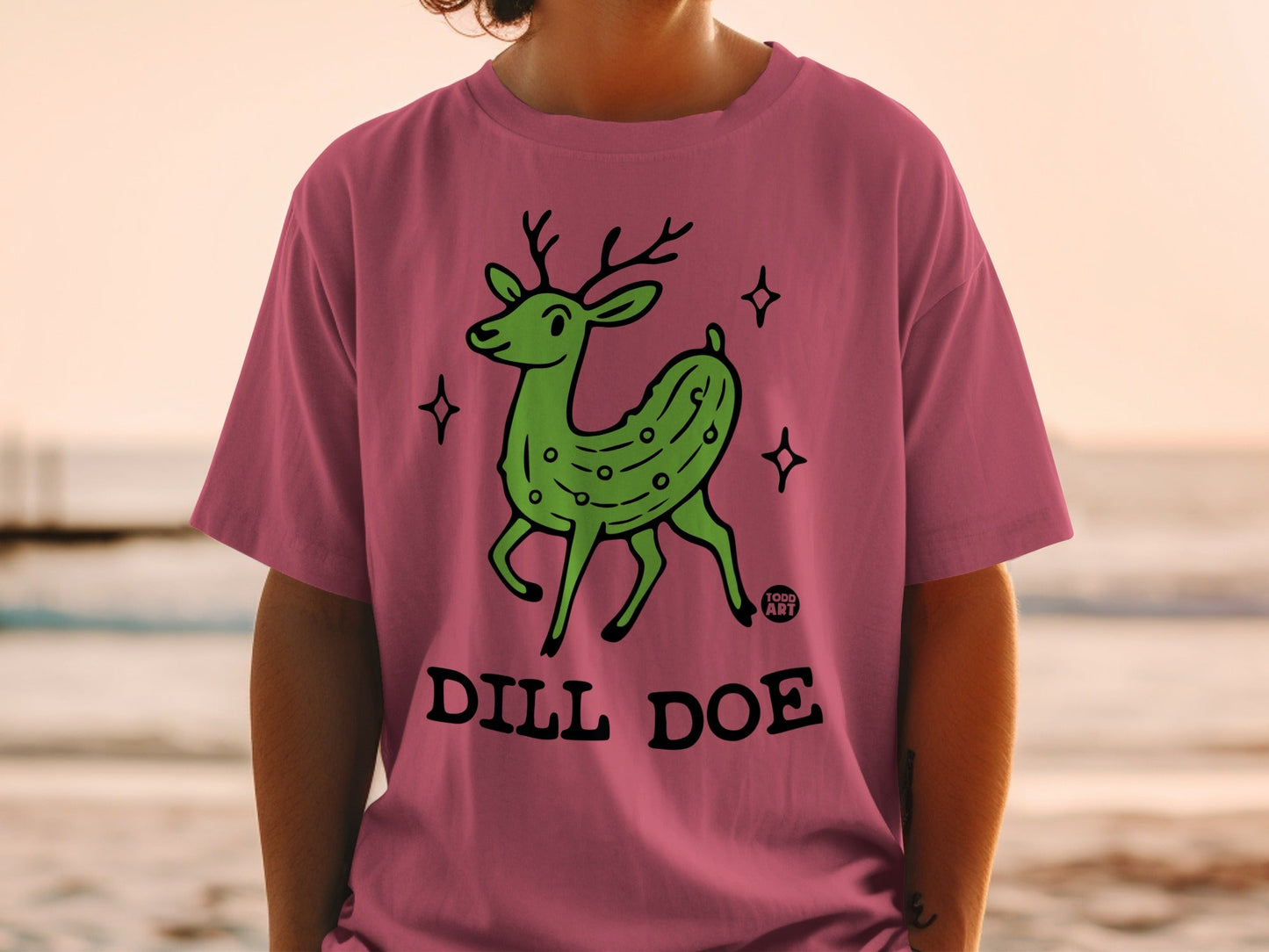 Green cartoon deer with pickle body, wearing a "Dill Doe" t-shirt.