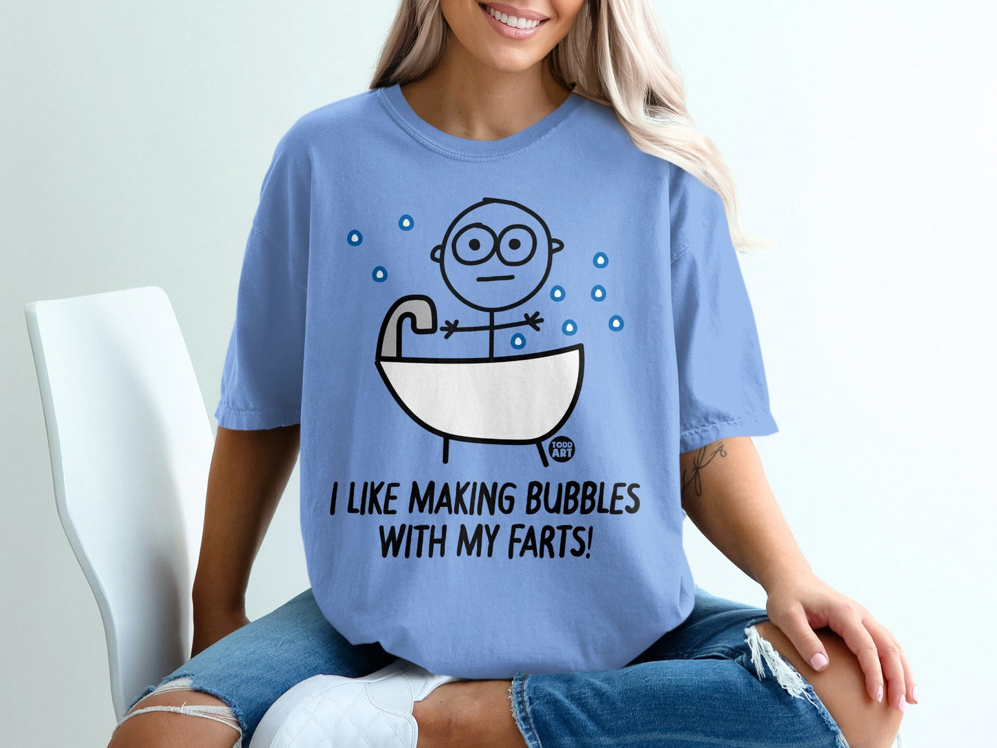 Blue t-shirt with a cartoon person in a bathtub saying "I like making bubbles with my farts!"