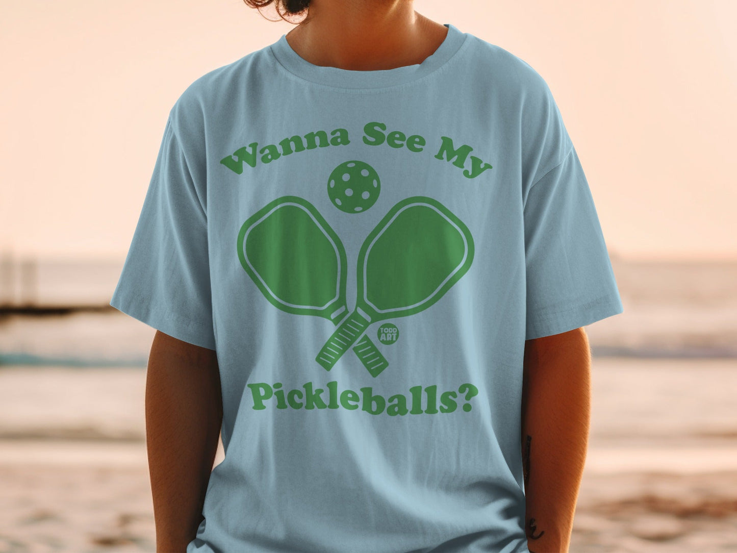 Light blue t-shirt with green text and pickleball graphic.