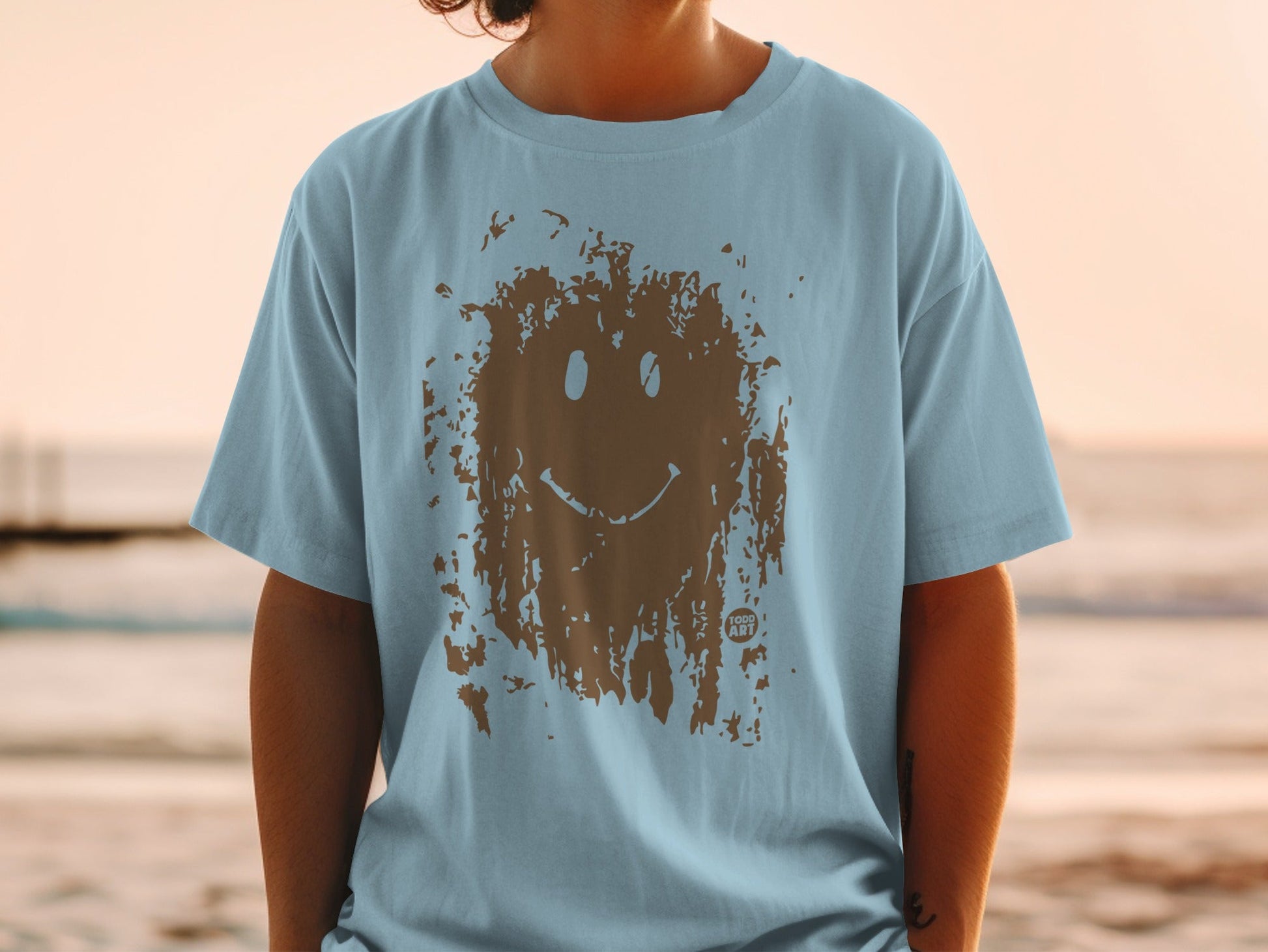 Light blue t-shirt with a brown distressed smiley face graphic.