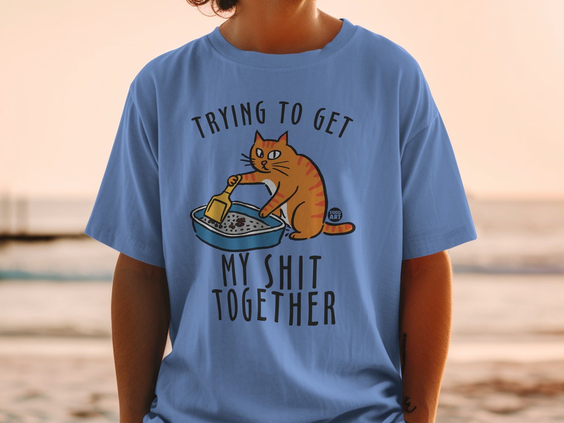 Orange cat cleaning litter box with text "Trying to Get My Shit Together."