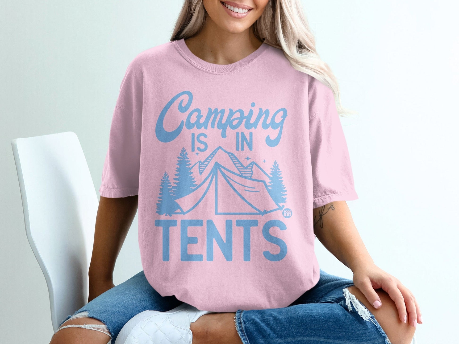 Pink t-shirt with blue "Camping is in TENTS" graphic, tent, and trees.