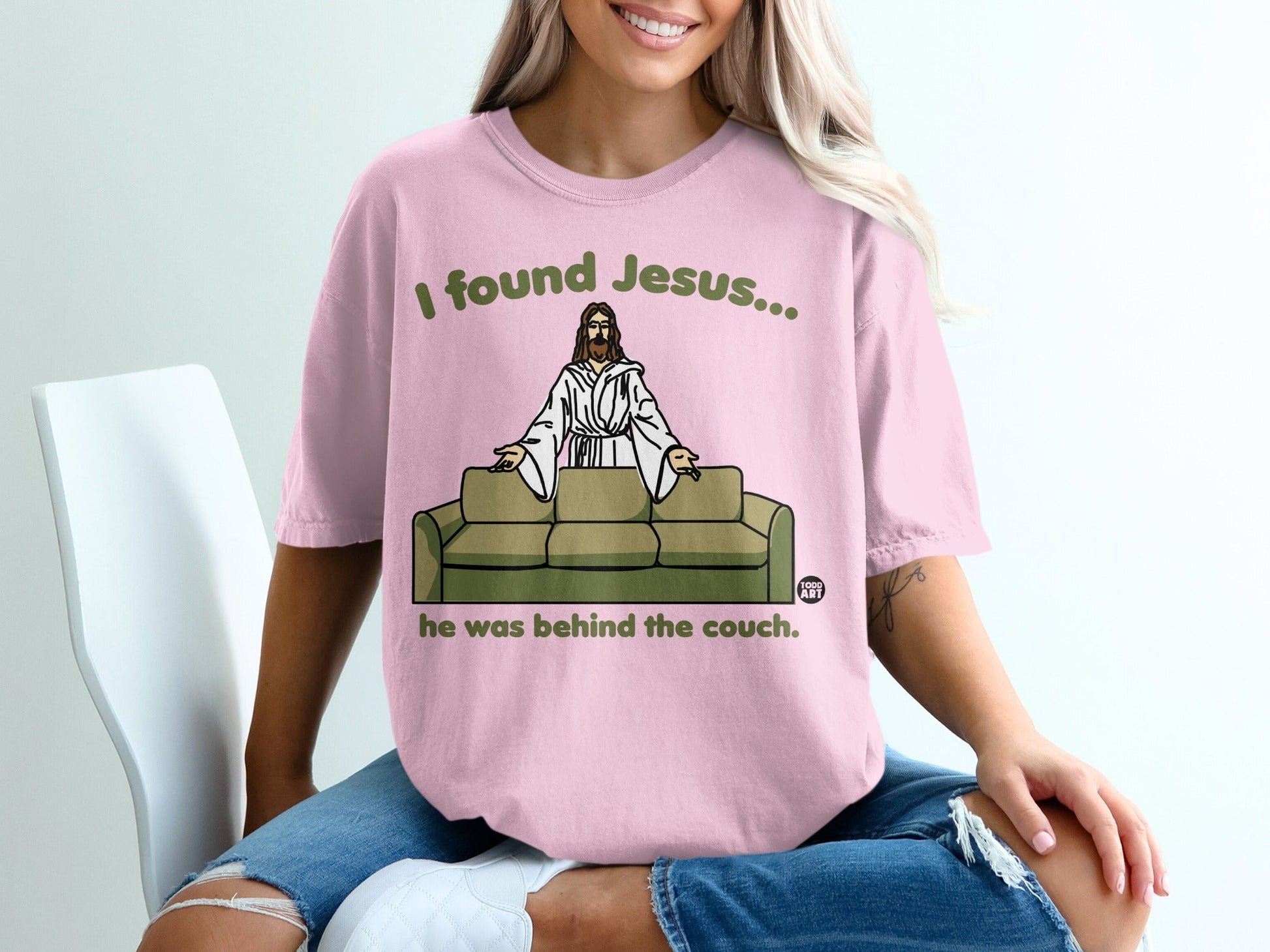 Pink t-shirt with text "I found Jesus... he was behind the couch."