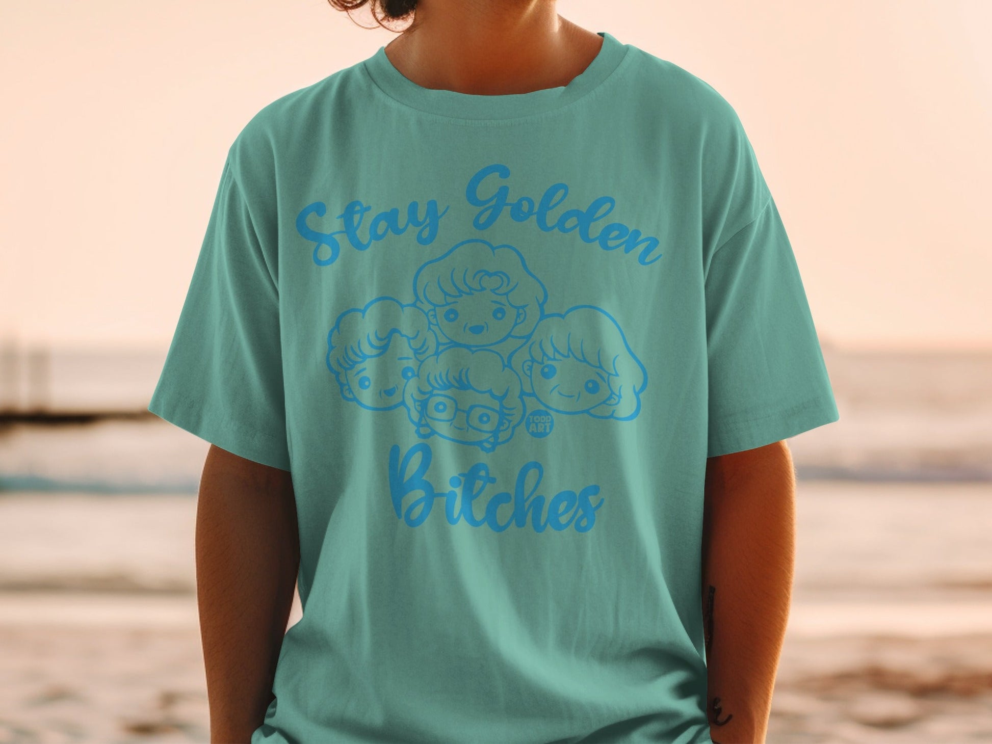 Teal t-shirt with "Stay Golden Bitches" and cartoon faces of The Golden Girls.