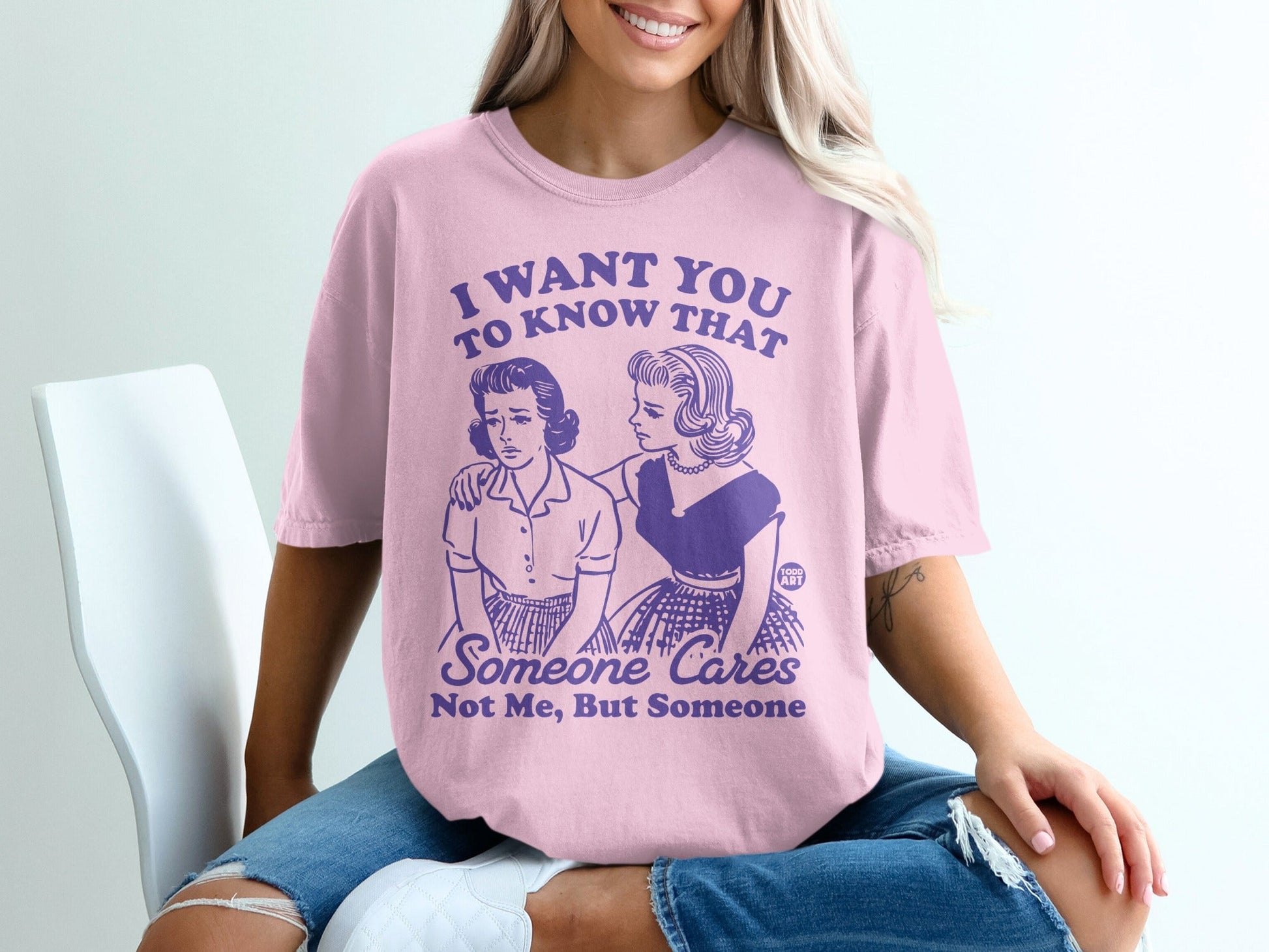 Pink graphic tee with distressed illustration and text about someone caring.