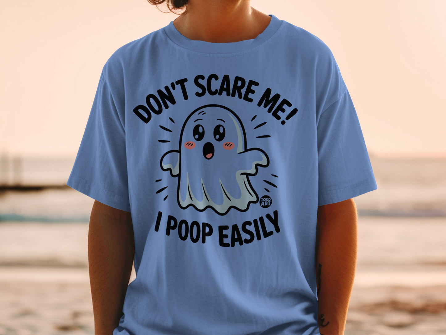 Light blue t-shirt with a cartoon ghost saying "Don't scare me! I poop easily."