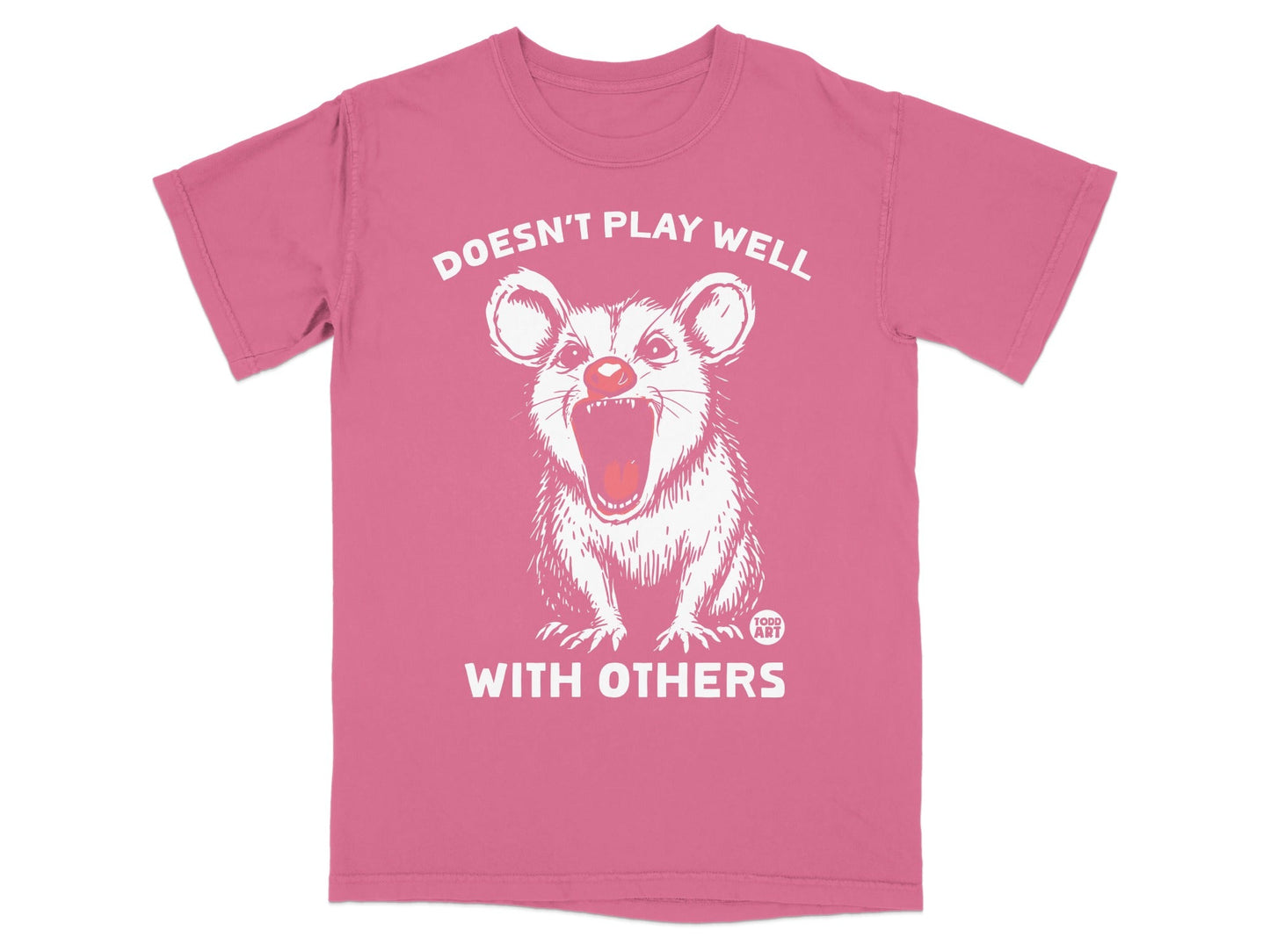Pink t-shirt with opossum illustration and text "DOESN'T PLAY WELL WITH OTHERS".