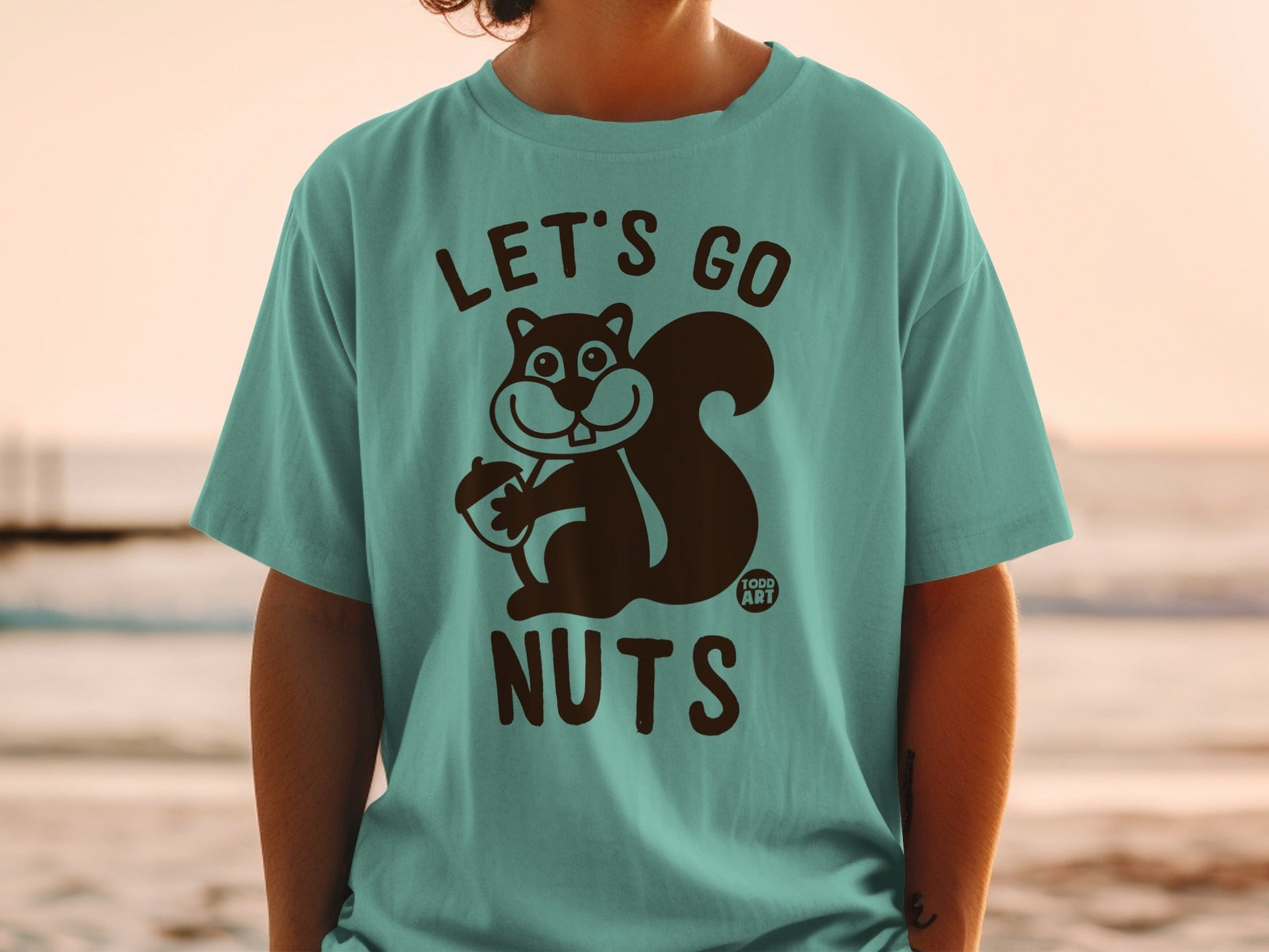 Teal t-shirt with a squirrel holding an acorn and the text "LET'S GO NUTS".