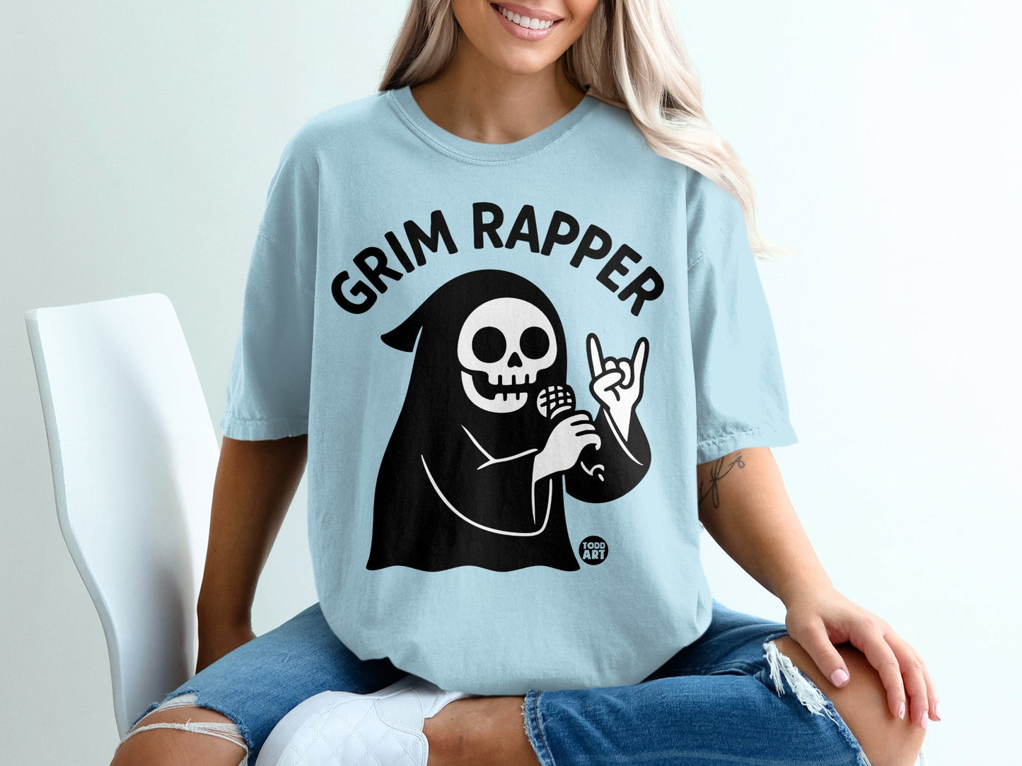 Grim Rapper graphic on a light blue t-shirt with microphone and rock-on hand.