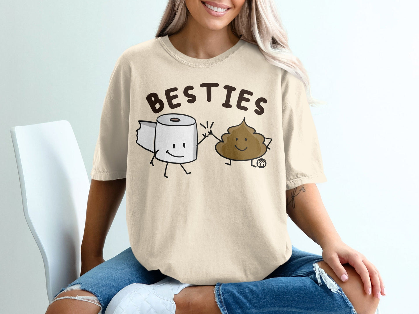 Toilet paper roll and smiling poop character on beige t-shirt.
