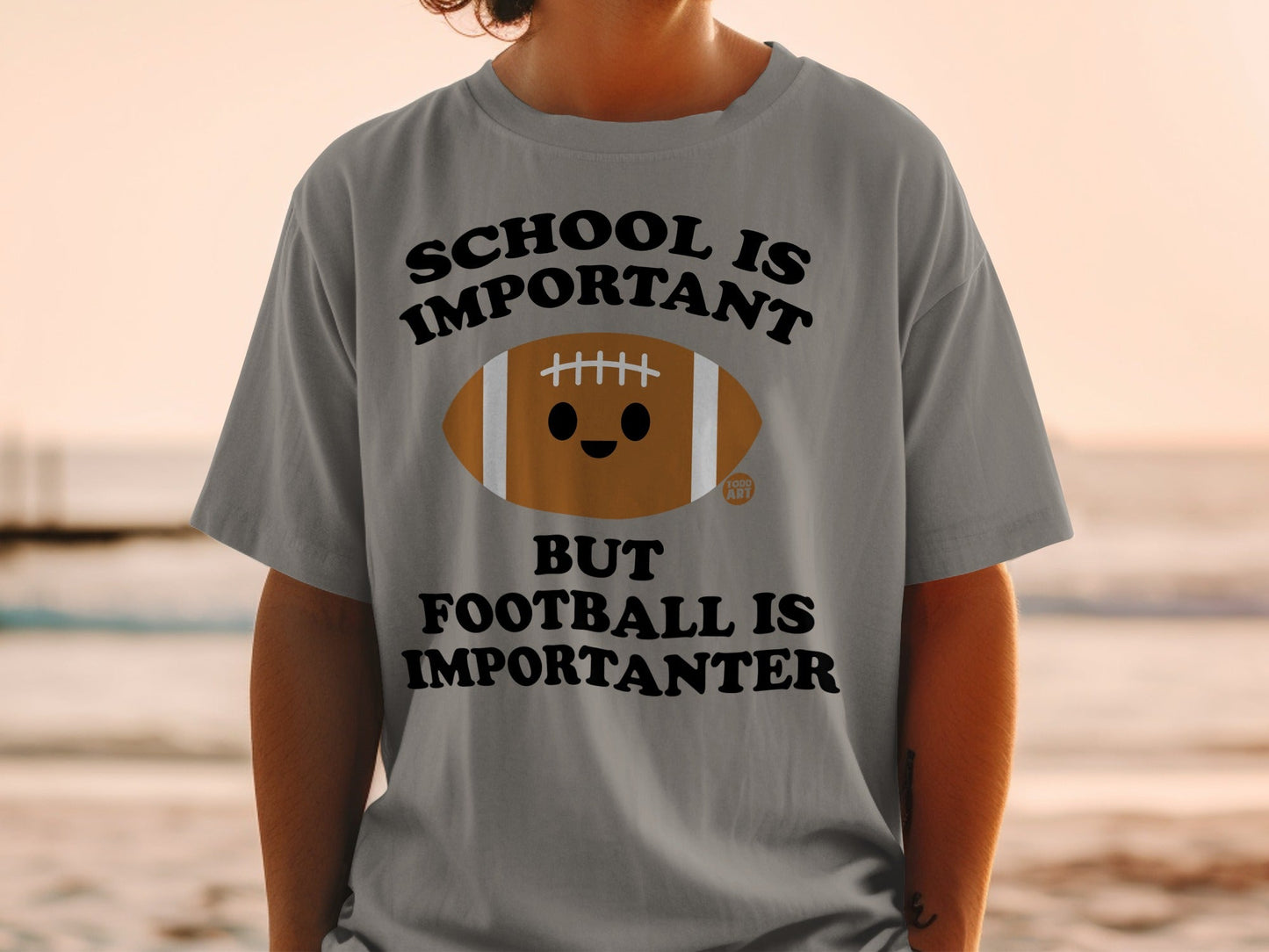 Grey t-shirt with "SCHOOL IS IMPORTANT BUT FOOTBALL IS IMPORTANTER" and a cute football graphic.