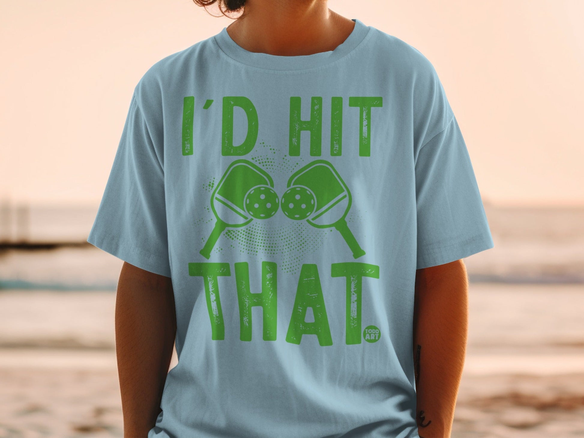 Light blue t-shirt with "I'D HIT THAT" and two pickleballs and paddles.