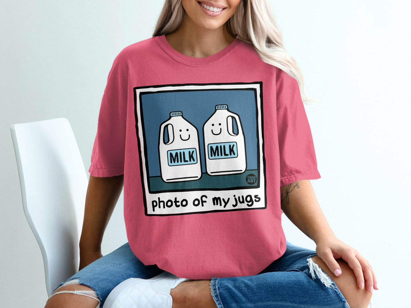 Two cartoon milk jugs with smiling faces on a pink t-shirt.