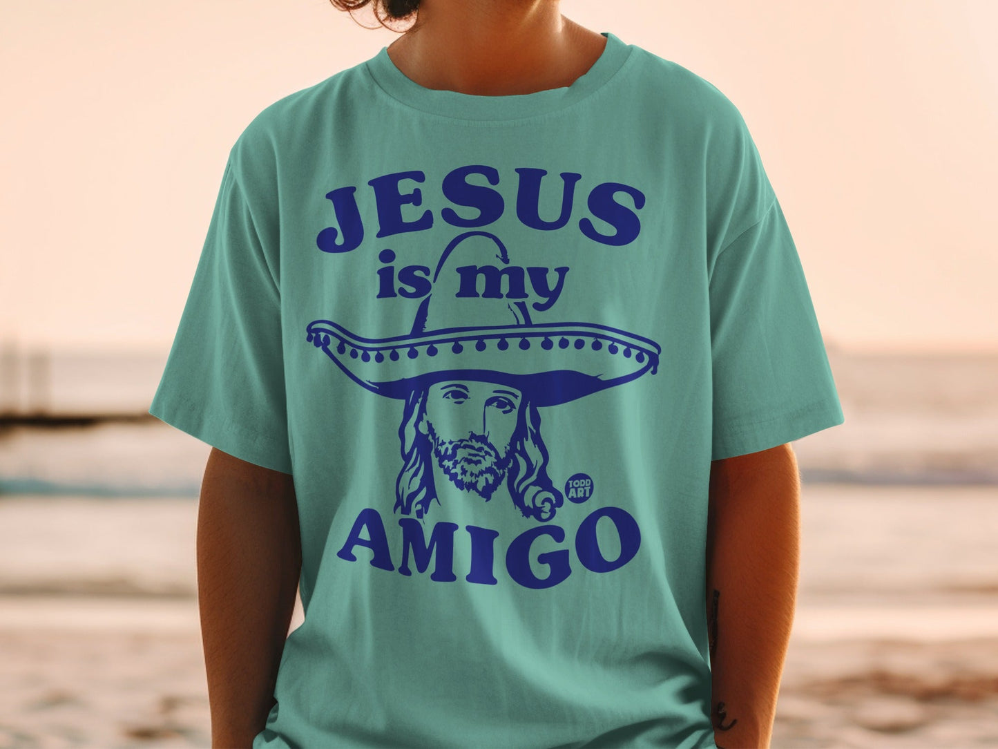 Teal t-shirt with Jesus in a sombrero, "Jesus is my amigo" text.