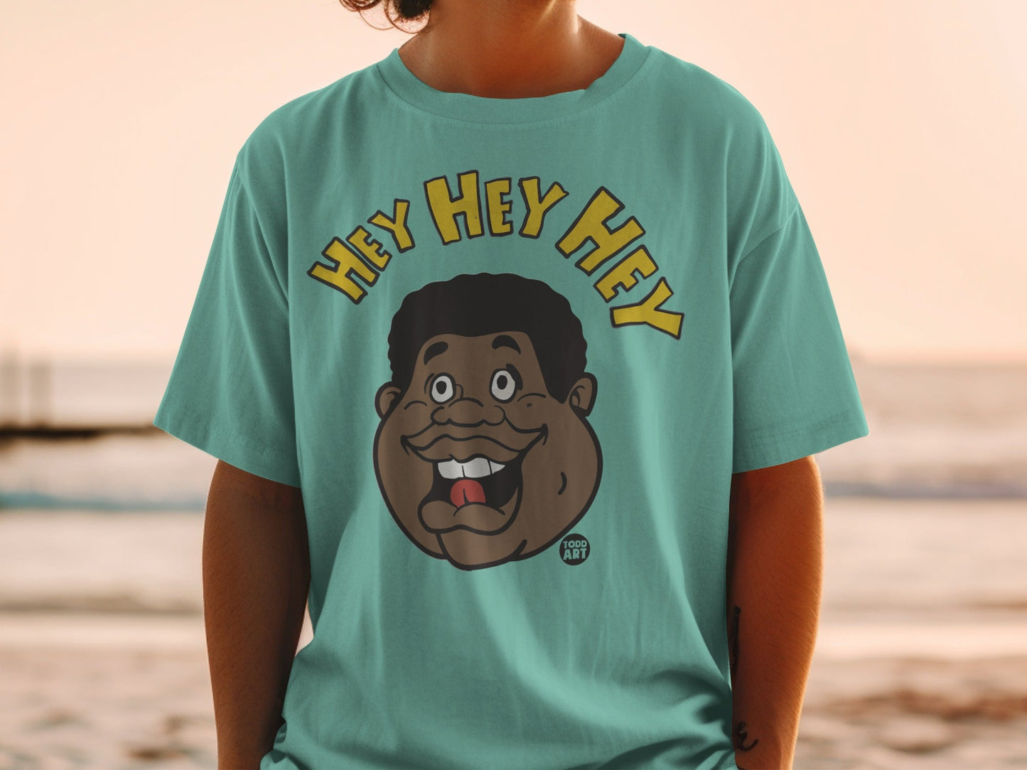 Teal t-shirt featuring a cartoon face with "HEY HEY HEY" text.