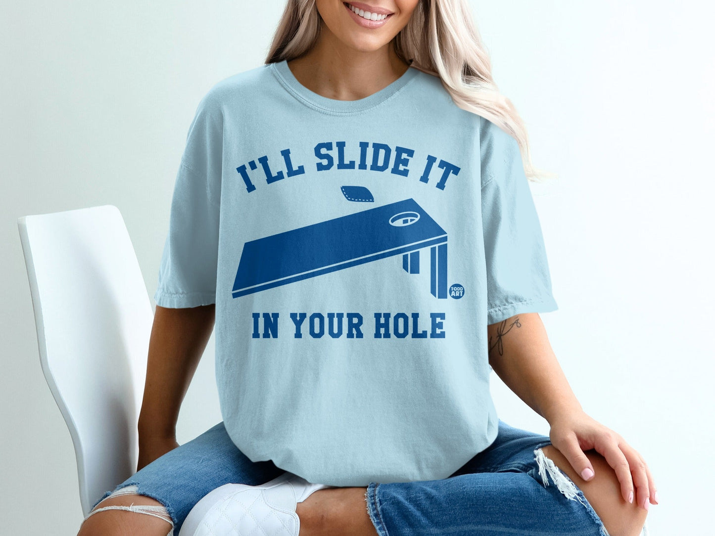 Light blue t-shirt with "I'll slide it in your hole" and a cornhole board graphic.