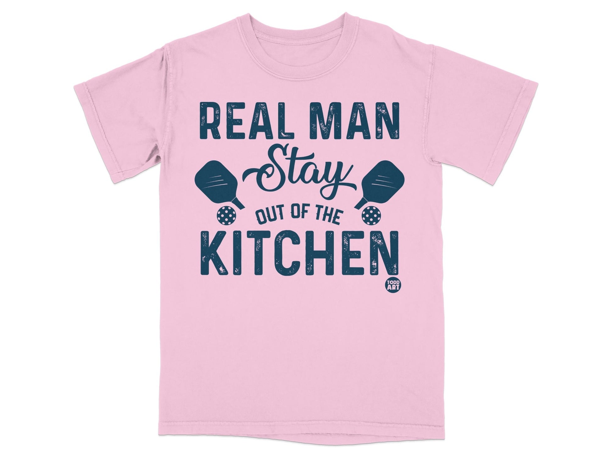 Pink t-shirt with "Real Man Stay Out Of The Kitchen" text and pickleball paddles.