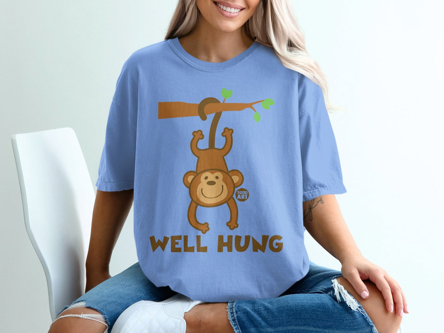 Blue t-shirt with a cartoon monkey hanging from a branch, reads "WELL HUNG".
