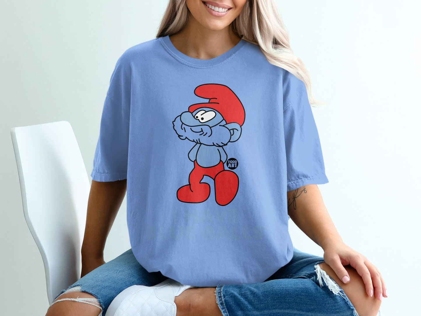 Blue t-shirt with a cartoon Smurf character printed on it.