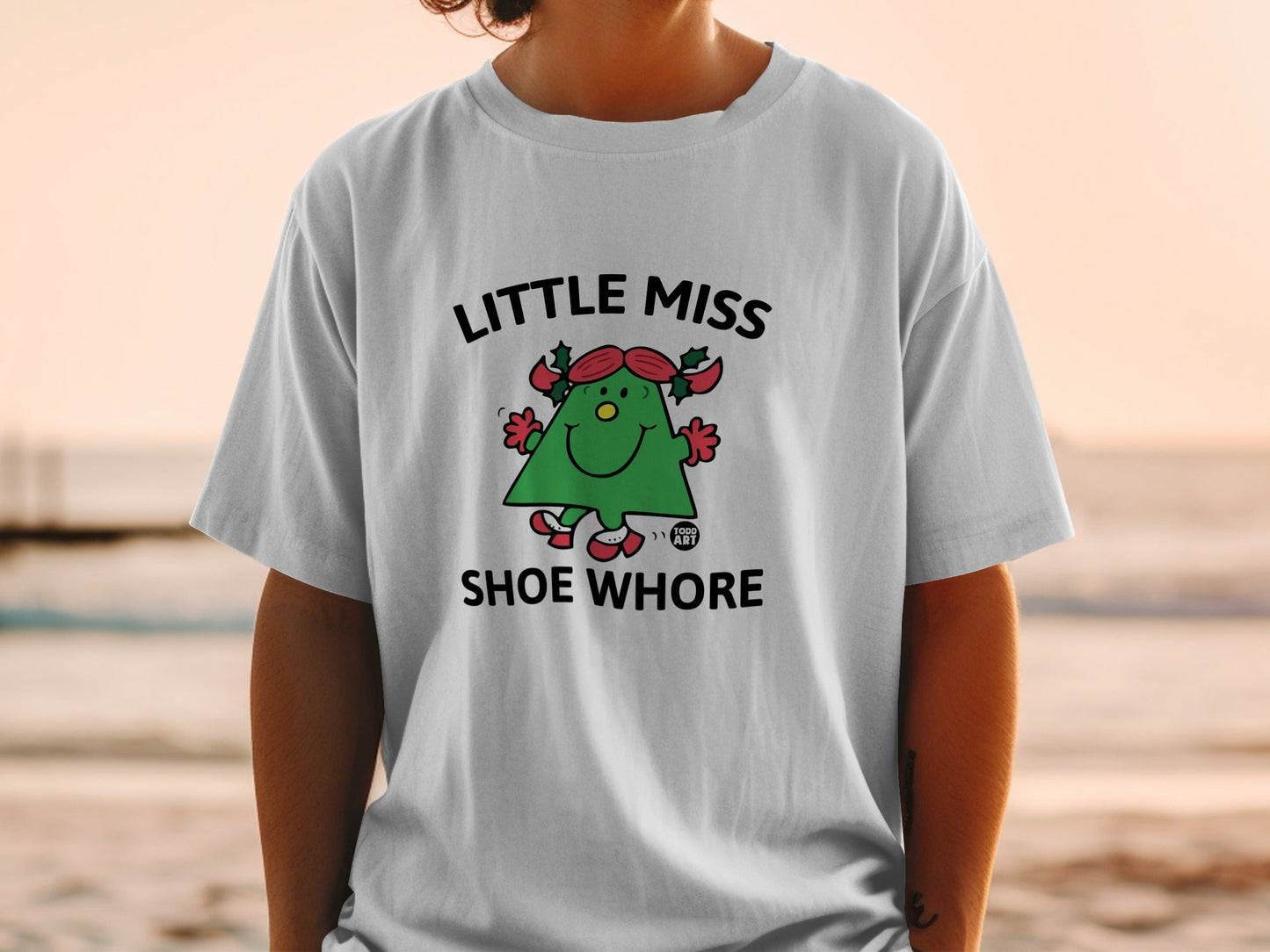 Little Miss Shoe Whore graphic t-shirt with cartoon character on light grey shirt.