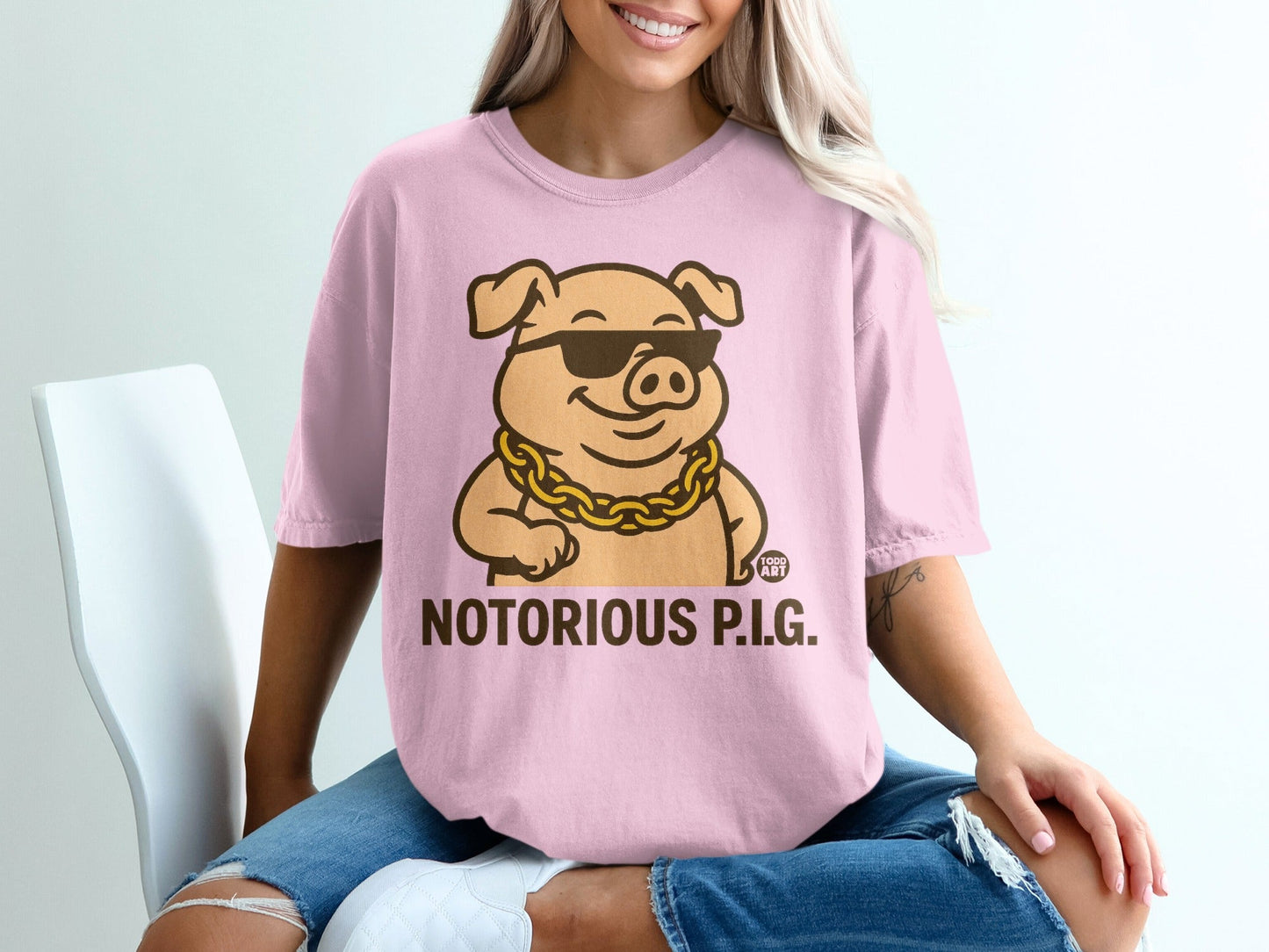 Pink t-shirt with cartoon pig wearing sunglasses and a gold chain, text "NOTORIOUS P.I.G.".