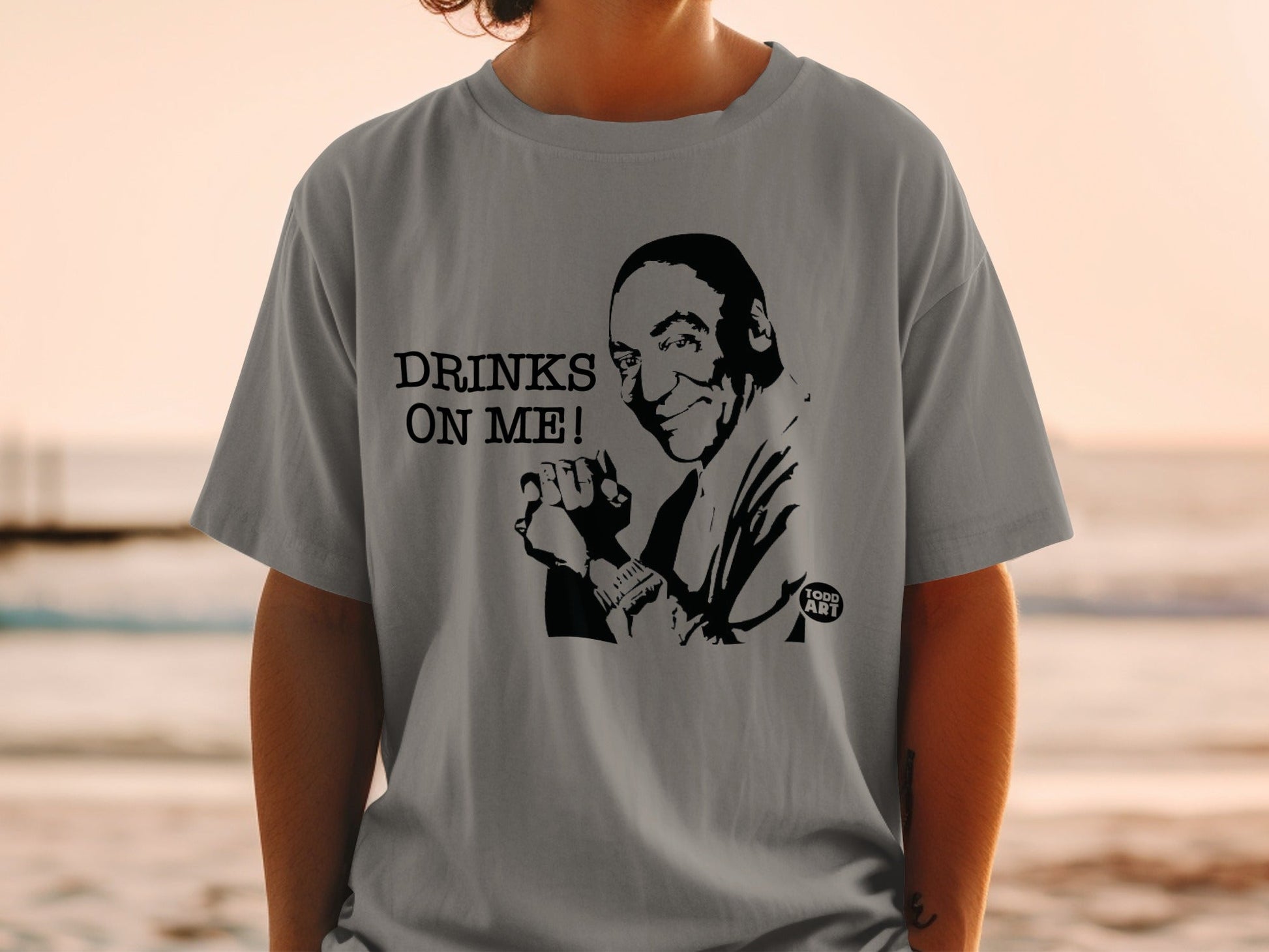 Grey t-shirt with black graphic of a man saying "Drinks on me!"