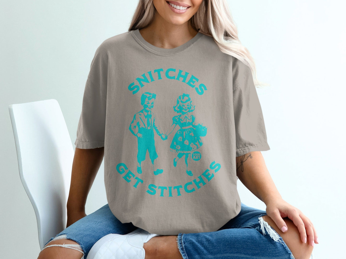 Light brown t-shirt with "SNITCHES GET STITCHES" graphic of two children.