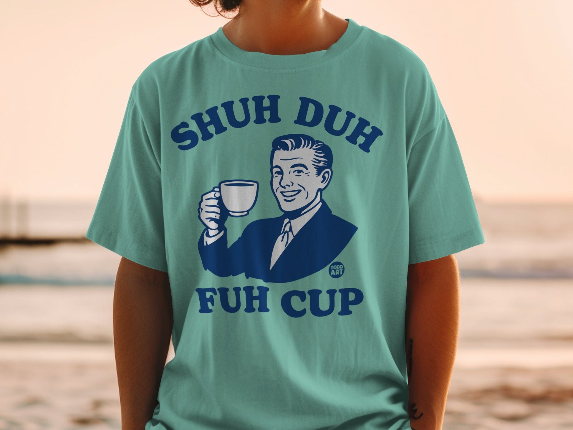 Teal t-shirt with graphic of man holding coffee mug, "SHUH DUH FUH CUP" text.